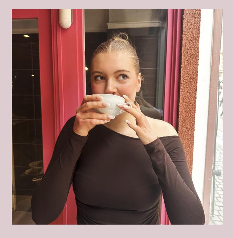 Kvinna som dricker kaffe vid La Fleurs rosa dörr